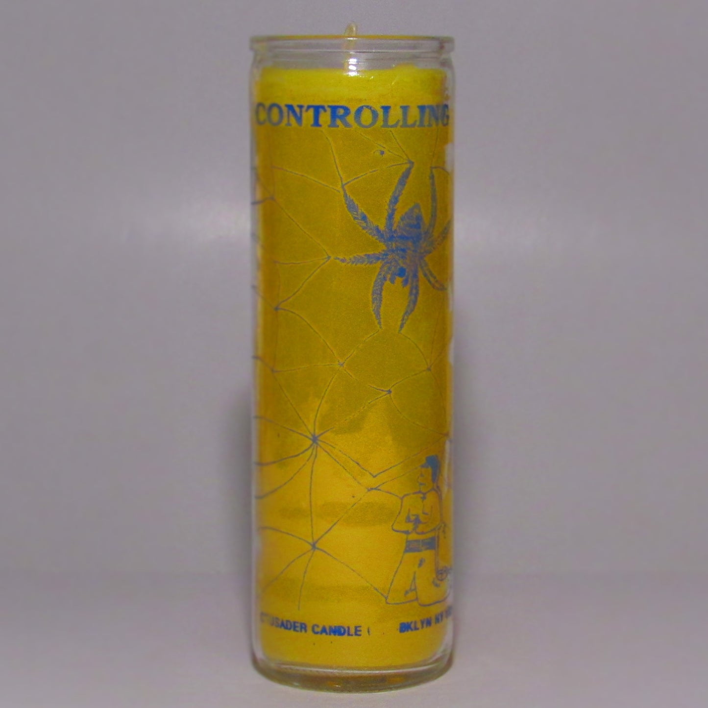 Yellow candle with spider design and text
