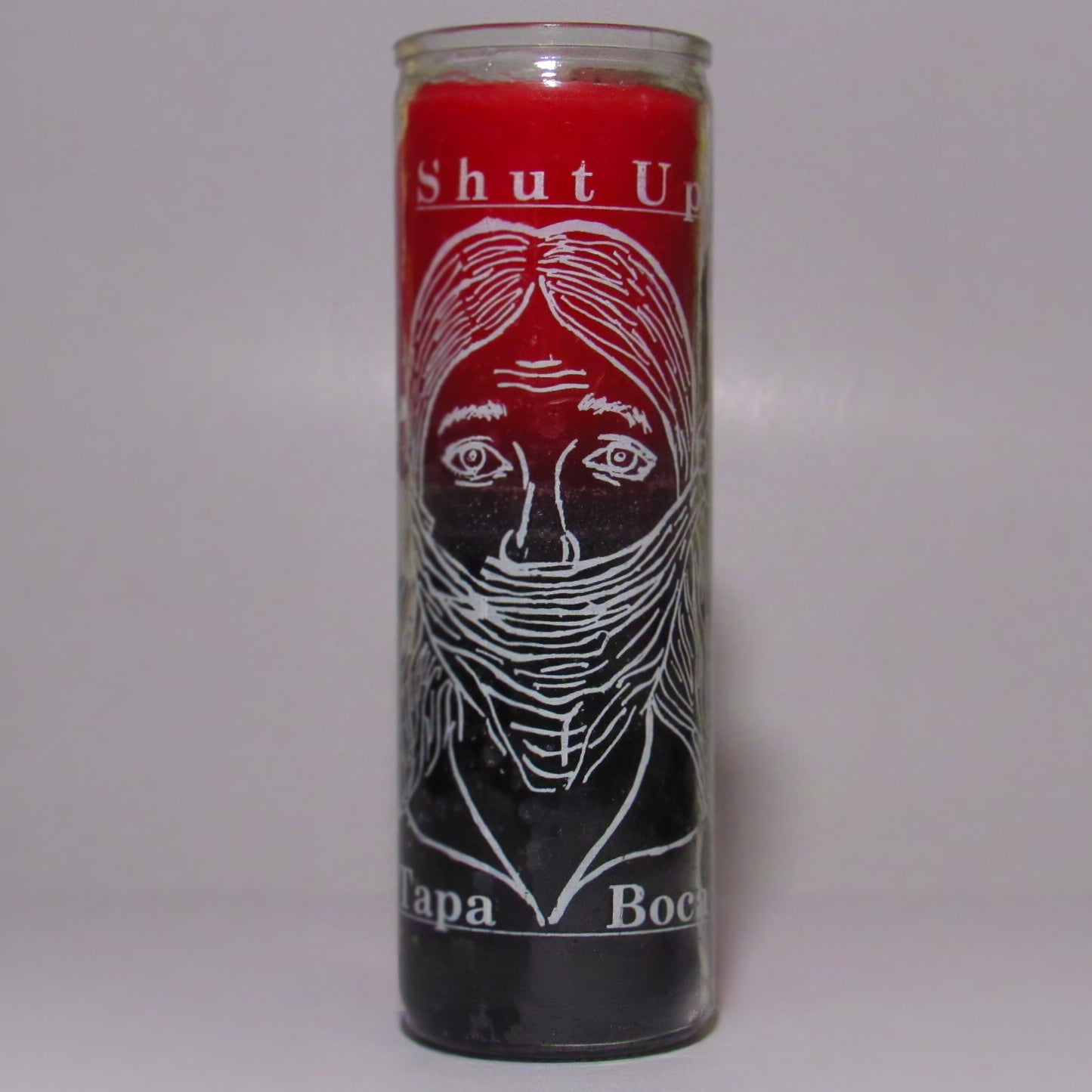 Candle with a face design and text 'Shut Up Tapa Boca'