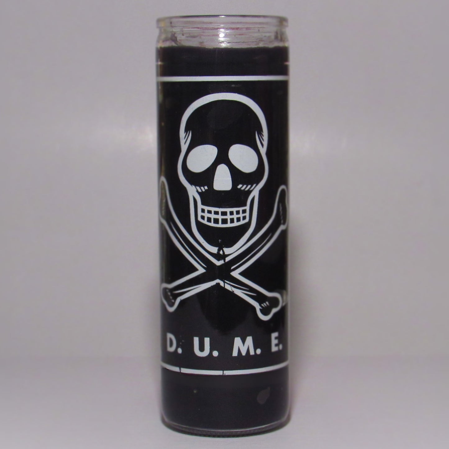 Black candle with a skull and crossbones design and 'D. U. M. E.' text 