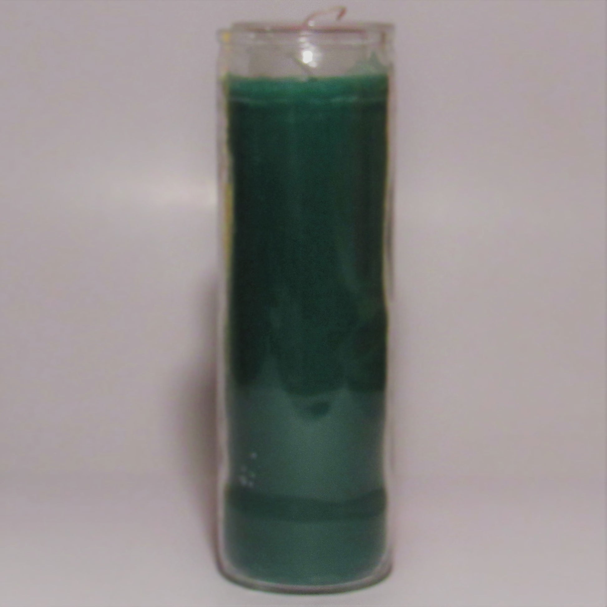 Green candle in a glass container on a light gray background